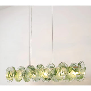Lumière Éclat rectangular glass disc chandelier in Emerald Green finish suspended over dining table with sculptural layered glass discs