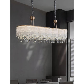 Luxury K9 crystal linear chandelier installed above a modern dining table with cascading crystal droplets