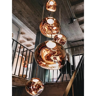 Rose gold chandelier with multiple glass spheres cascading along a staircase, adding a luxury glow to a contemporary space