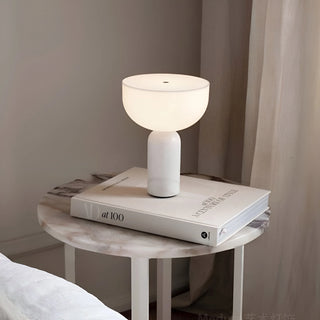 Marble cordless rechargeable table lamp with white marble base and frosted glass shade placed on a bedside table