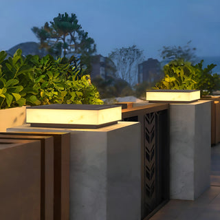 Elegant marble-finish outdoor solar pillar lights illuminating a modern villa terrace at dusk, surrounded by greenery