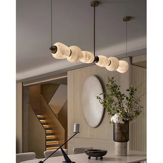 Modern marble linear chandelier over kitchen island with solid copper frame and warm LED glow
