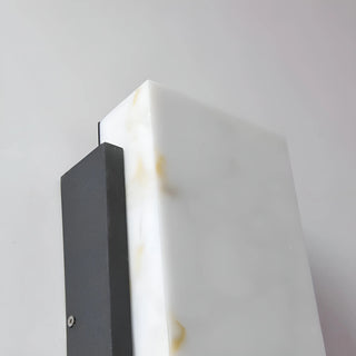 Upper corner detail of wall sconce showcasing polished marble texture and powder-coated frame