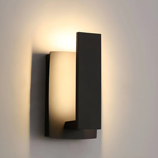 Modern wall sconce lit up with soft warm light on neutral wall