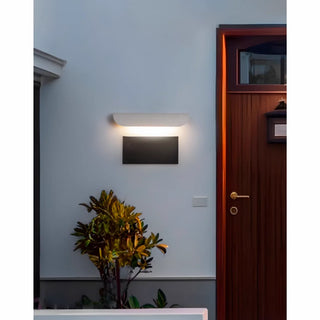 Warm light white wall lamp mounted near wooden front door in modern outdoor setting