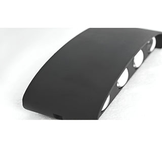 Angled view of the curved matte black aluminum body of the minimalist LED wall light with visible lens openings