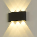 6-beam black LED wall light mounted and lit, creating a crisscross light pattern above and below the fixture