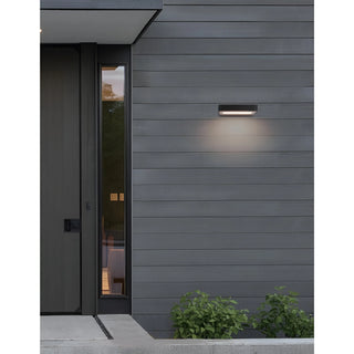 Modern ultra-slim LED wall light mounted on exterior wood siding, emitting warm white light