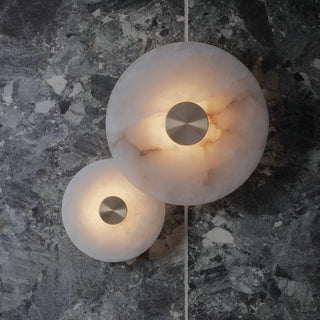 Pair of MIRODEMI alabaster and brass wall sconces mounted on a dark marble wall, radiating warm light through natural stone texture