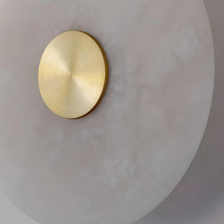 Close-up of MIRODEMI wall light showing the brushed brass centerpiece and translucent alabaster surface with natural veining