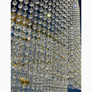 Golden/chrome crystal chandelier illuminated on staircase