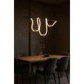 MIRODEMI modern irregular LED chandelier with glowing silicone curves and gold spheres above a warm wooden dining table in a dark minimalist interior