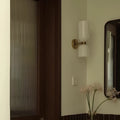 Modern brushed brass and white glass wall sconce installed in a contemporary entryway interior