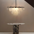 Handcrafted glass chandelier in soft light tones hanging over a striking round marble dining table