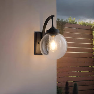 Warm LED outdoor wall light illuminating wooden exterior wall at dusk, modern stainless steel glass globe design