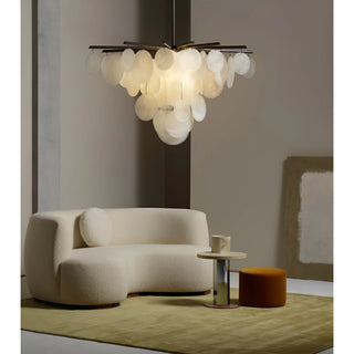 Modern glass chandelier with hand-fritted discs hanging above a minimalist boucle sofa in a neutral-toned interior