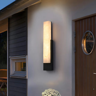 Modern black LED wall light with marble-look glow mounted beside a contemporary exterior entrance at night