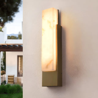Outdoor view of the modern marble-look LED wall light with a brass base and warm alabaster-style glow