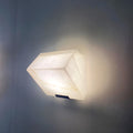 Close-up of single modern marble wall sconce with natural stone texture and warm LED glow
