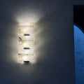 Front view of three-light marble wall sconce with soft architectural wall illumination