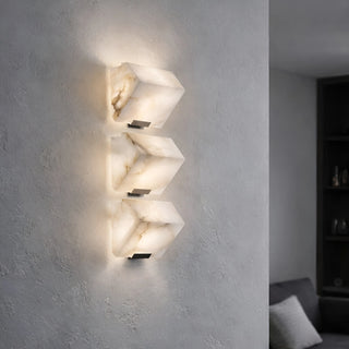 Three-light marble wall sconce installed in modern interior with warm ambient lighting