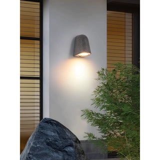 Microcement wall light with warm glow in contemporary garden setting