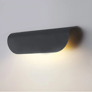 Black version of the Modern Outdoor Wall Light producing a cozy warm light on a white wall