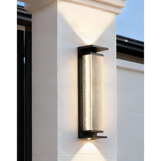 Modern outdoor wall light with textured glass producing both upward and downward light beam, creating a dramatic effect on a white wall