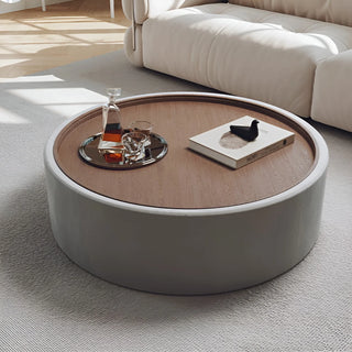 Gray modern round coffee table with walnut veneer top and matte fabric finish in minimalist living room