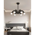 Black sculptural chandelier installed in modern bedroom interior above bed, contemporary ceiling lighting