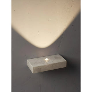 closeup of minimalist stone wall lamp illuminating wall with smooth soft light