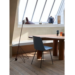 Modern tripod floor lamp beside dining table in contemporary interior with large window