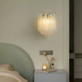 Elegant Murano style textured glass wall sconce mounted beside a bed, casting a soft warm glow in a minimalist bedroom interior