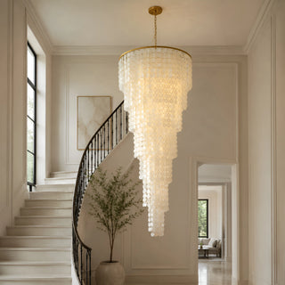 Nacara capiz shell spiral cascade chandelier hanging in a grand curved staircase foyer