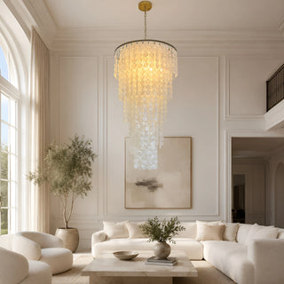 Nacara capiz shell chandelier in a double-height living room with cream sofas and an olive tree