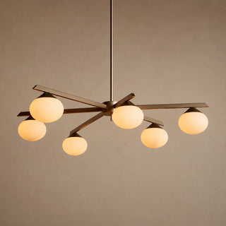 Novara brass six-light chandelier with opal glass globes on radiating arms, lit studio view