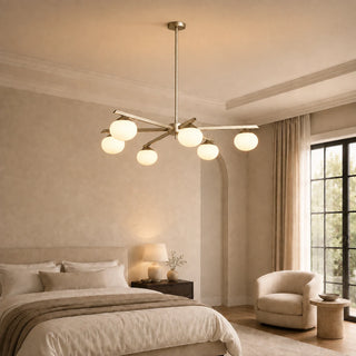 Novara brass six-light opal-globe chandelier lighting a warm modern bedroom
