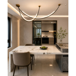 Ondara curved LED wave chandelier with brass canopies above a marble dining table