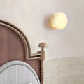French-style onyx wall sconce above vintage curved headboard