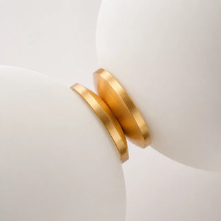 Macro detail of the brushed brass connector between two frosted glass orbs on the Orbara pendant