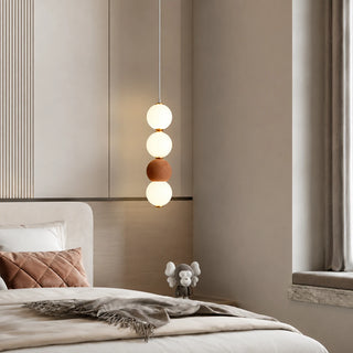 Brick red Orbara stacked-sphere pendant beside a bed in a warm modern bedroom