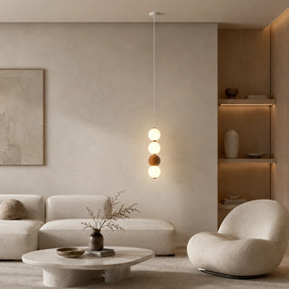Brick red Orbara stacked-sphere pendant in a warm minimalist living room with a boucle chair