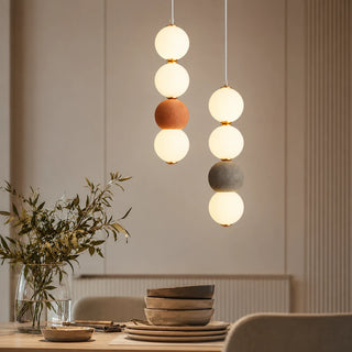 Orbara stacked-sphere pendants in brick red and gray over a wood dining table in a warm modern room