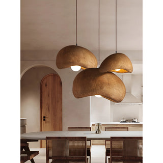 three curved organic-shaped pendant lights in warm brown tones suspended above a dining table in a minimalist modern kitchen with soft ambient light