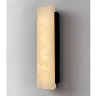 Illuminated faux alabaster wall sconce emitting soft ambient warm light