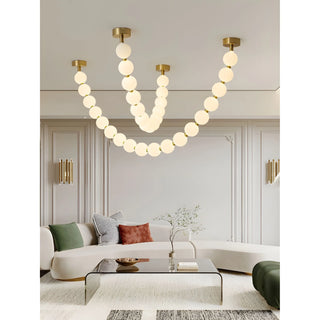 Modern pearl necklace chandelier with warm LED spheres illuminating a contemporary living room