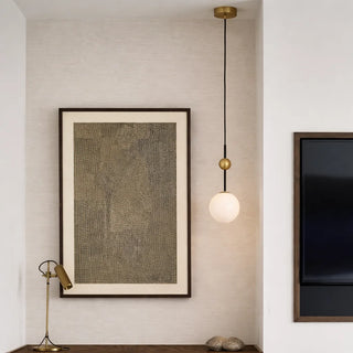 Sleek pendant light with white glass shade hanging in the corner of a minimalist bedroom