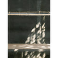 Zoomed-in section of the pendant light casting artistic shadows onto a rustic wall and light wood table