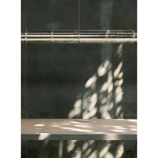 Zoomed-in section of the pendant light casting artistic shadows onto a rustic wall and light wood table