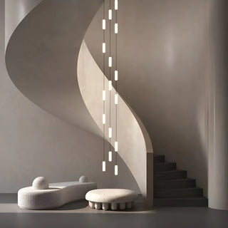 Pluvara capsule chandelier beside a sculptural spiral staircase in a minimalist concrete interior